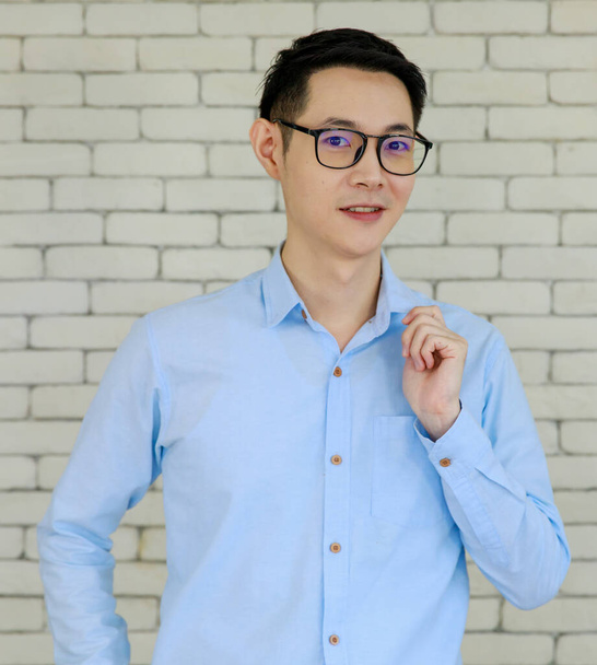 Authentic photo taken with natural light of young and handsome Asian man wearing eyeglasses pose with self-confidence and friendly to camera on brick wall background. - Photo, Image
