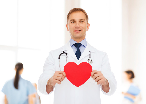 smiling male doctor with red heart and stethoscope - Foto, afbeelding