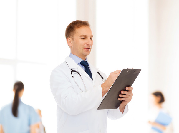 smiling male doctor with clipboard and stethoscope - Foto, Imagen