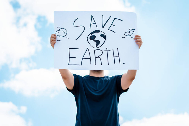 Mann mit einem Schild, das besagt, dass der Planet Erde gerettet werden soll - Foto, Bild