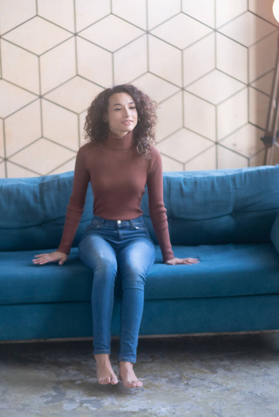junge schöne Frau sitzt in Jeans auf der Couch - Foto, Bild