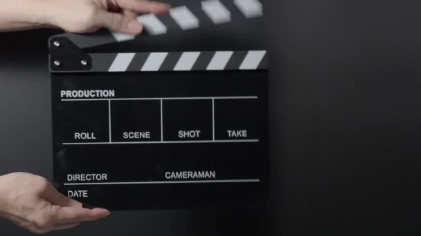 Movie slate or clapperboard hitting. Close up hand holding empty film slate and clapping it on black background. Open and close film slate for video production. film production. Movie shooting. - Footage, Video