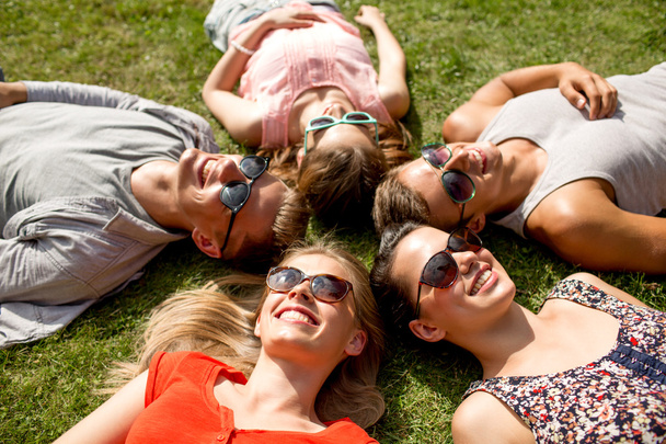 group of smiling friends lying on grass outdoors - Φωτογραφία, εικόνα