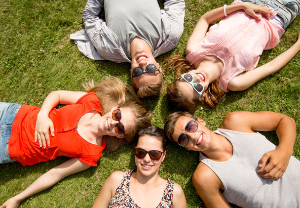 grupo de amigos sorridentes deitado na grama ao ar livre
 - Foto, Imagem