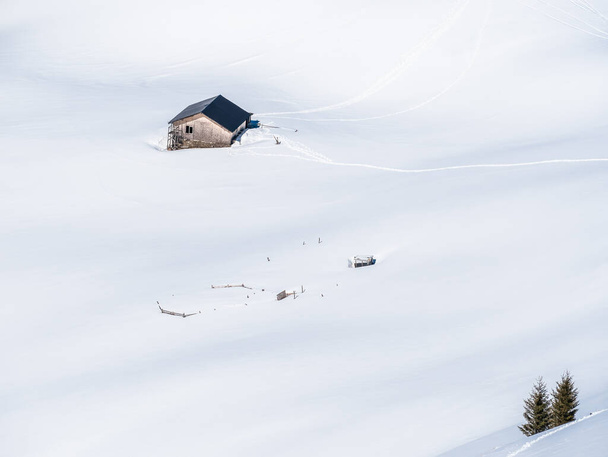Letecký pohled s chatou nebo chatou v horách uprostřed moře bílého čerstvého sněhu.Zimní krajina v pohoří Bucegi. - Fotografie, Obrázek