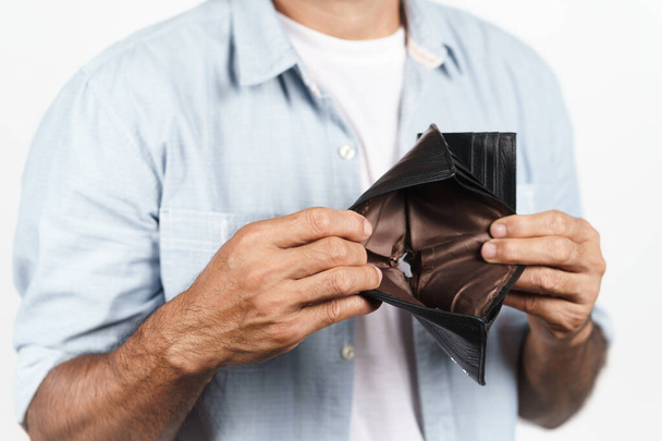 Uomo maturo sconvolto che tiene il portafoglio vuoto su sfondo bianco. crisi finanziaria, fallimento, senza soldi, cattiva economia Concetto - Foto, immagini