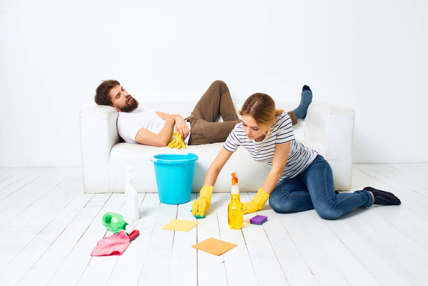 um jovem casal perto do sofá detergente trapos esponjas prestação de serviços - Foto, Imagem