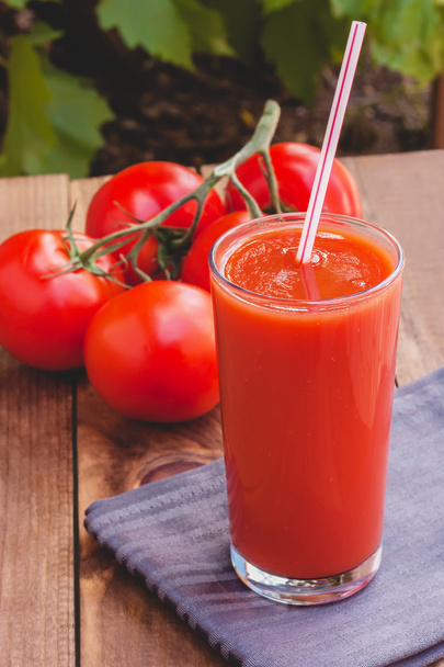 Стакан томатного сока с соломой на деревянном фоне
 - Фото, изображение