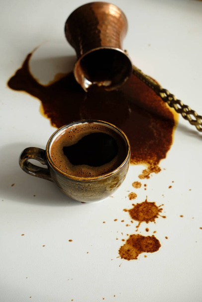 Tasse de café turc et cezve renversé avec café renversé sur fond blanc - Photo, image