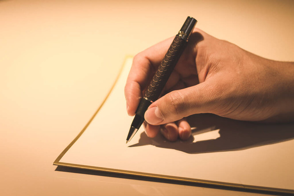 A closeup of a man's hand writing with an elegant fountain pen with a leather-wrapped grip - Foto, Imagen