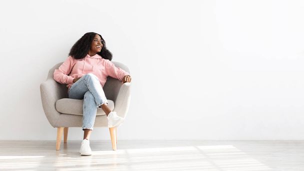 Cheerful black woman posing resting in arm chair at home - Foto, imagen