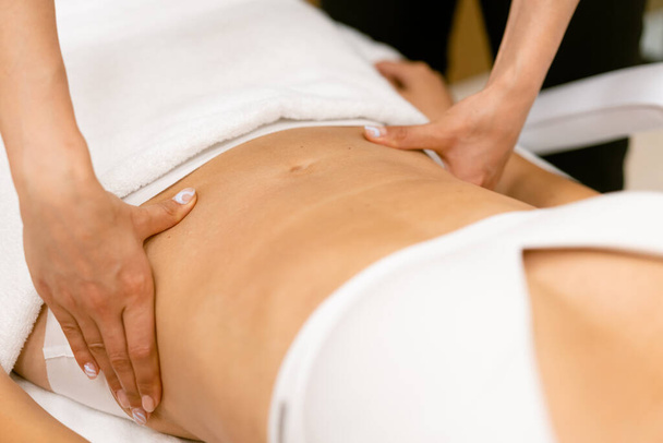 Жінка середнього віку має масаж живота в салоні краси
. - Фото, зображення