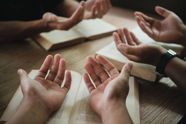 クリスチャンは神の祝福を求めて手を携えて祈る会衆です。献身的または祈りの会議の概念. - 写真・画像