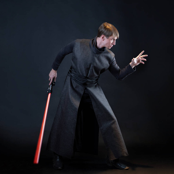 A villain with a red lightsaber, a young man in a long robe does fighting poses, - 写真・画像