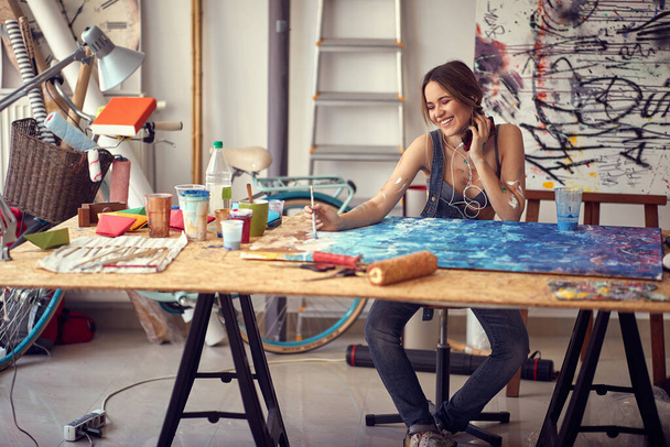 Young tempting female artist working in the studio - 写真・画像