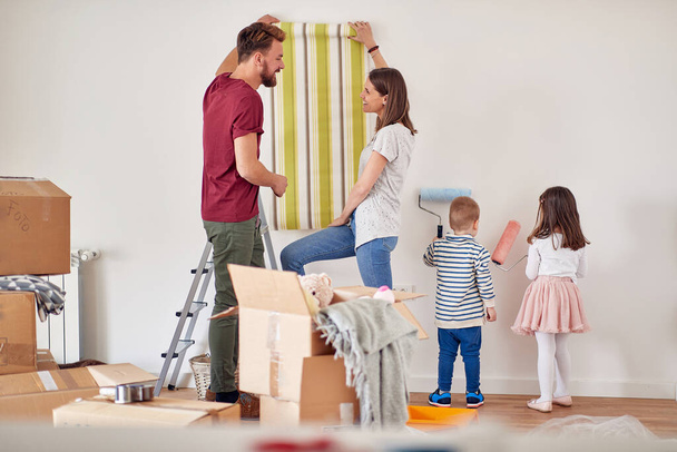 Happy caucasian family painting walls together; Remodeling home concept - Φωτογραφία, εικόνα