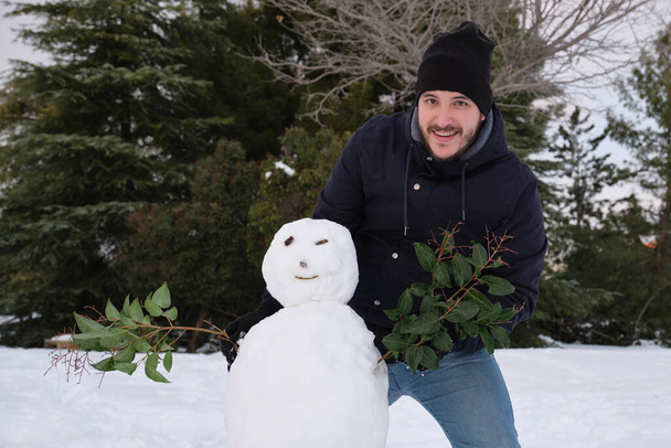 Fiatal kaukázusi ember, hogy egy mosolygós hóember károsítja ágak. - Fotó, kép