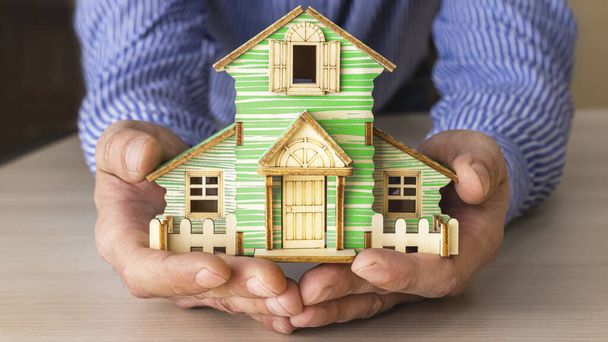 Das Konzept der Hypotheken- und Mietwohnungen und Immobilien. Hypothekenkredite. Der Grundriss eines Holzhauses in den Händen eines Mannes - Foto, Bild