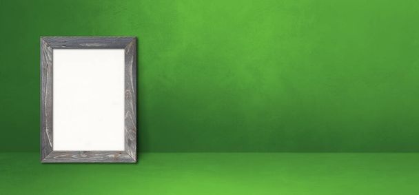 Wooden picture frame leaning on a green wall. Blank mockup template. Horizontal banner - Fotó, kép