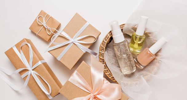 Organic cosmetics and gifts for the holiday. Flat lay, top view clear glass pump bottle, brush jar, moisturizing serum jar in a paper basket on a white background. Natural cosmetics SPA - 写真・画像