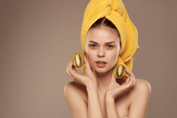 женщина с полотенцем на голове с фруктовым киви в руке обрезанный вид - Фото, изображение