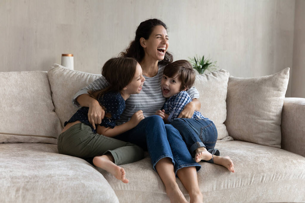 Overjoyed young hispanic mother having fun with laughing small kids. - Photo, image