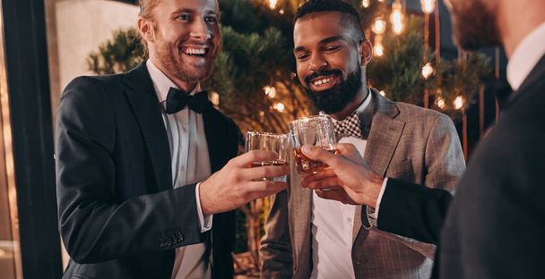 Three well-dressed men drinking whiskey and communicating while spending time on party - Foto, Imagem
