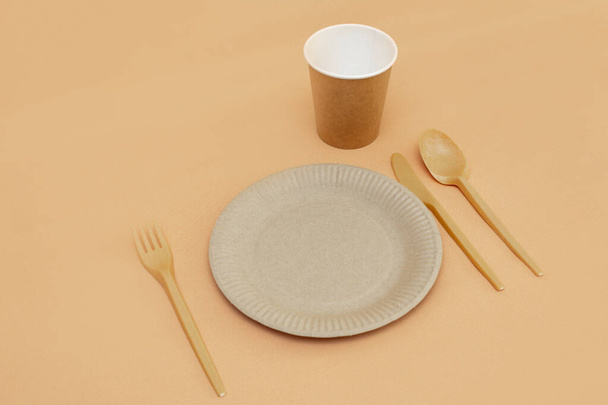 Recyclable fork, spoon, knife, plate and cup on a beige background. Kitchen utensils. Top view. Minimalist Style. Copy space. - Zdjęcie, obraz
