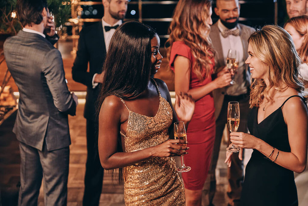 Group of beautiful young people in formalwear communicating and smiling while spending time on luxury party - Photo, Image