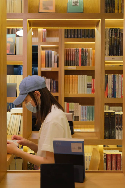 Młoda kobieta czyta książkę w bibliotece - Zdjęcie, obraz