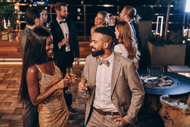 Beautiful young African couple in formalwear holding champagne flutes and smiling - Zdjęcie, obraz