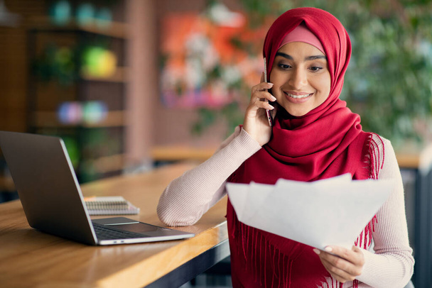 Fröhliche muslimische Frau sitzt im Café und arbeitet online - Foto, Bild