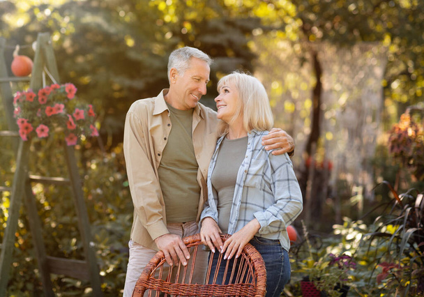 Glückliches Rentnerehepaar, das sich umarmt, auf dem Land ausruht und einander mit Liebe betrachtet - Foto, Bild