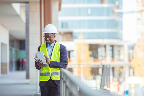 Portrait of smiling Engineer / Architect looking at camera. Working on a new office building. Happy mid adult engineer. Man engineer walking on construction site, holding tablet. - Foto, Imagen