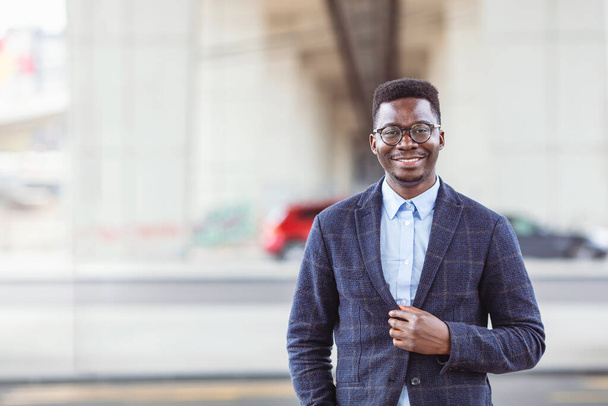 Portrait of smiling businessman. Handsome young man in eyeglasses looking at camera. Concept of confidence. Young African businessman exploring the city - Photo, Image