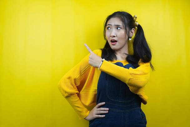 Pretty and cute young woman surprised, shocked, wow expression, hand pointing at empty space, presenting something, promoting product, advertisement, isolated - Foto, immagini