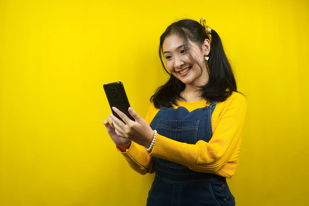 Pretty and cute young woman cheerful, confident, with hands holding smartphone, promoting product, presenting something, advertisement, isolated - Zdjęcie, obraz