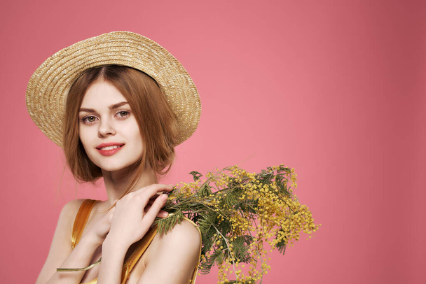 woman in hat with bouquet of flowers decoration luxury pink background - Foto, afbeelding