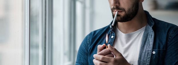 Młody człowiek z papierosem w ręku, samotny i przygnębiony. Uzależnienie od nikotyny - Zdjęcie, obraz
