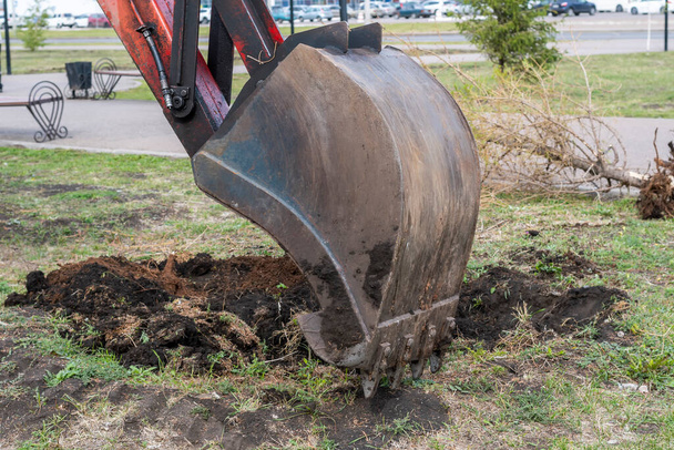 The iron bucket of the excavator digs into the ground. The process of digging a hole (trench). - Photo, Image