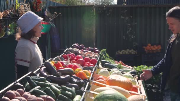 Kürbisse auf dem Markt kaufen. Ein Mann kauft auf einem Bauernmarkt einen Kürbis von einer Verkäuferin. - Filmmaterial, Video