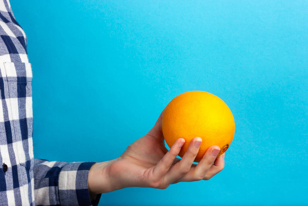 Kadın elinde turuncu bir el. Bir kadın elini portakala uzatır. - Fotoğraf, Görsel