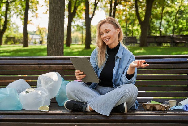 Woman relaxing at the sunny park while using tablet with enjoying - Photo, Image