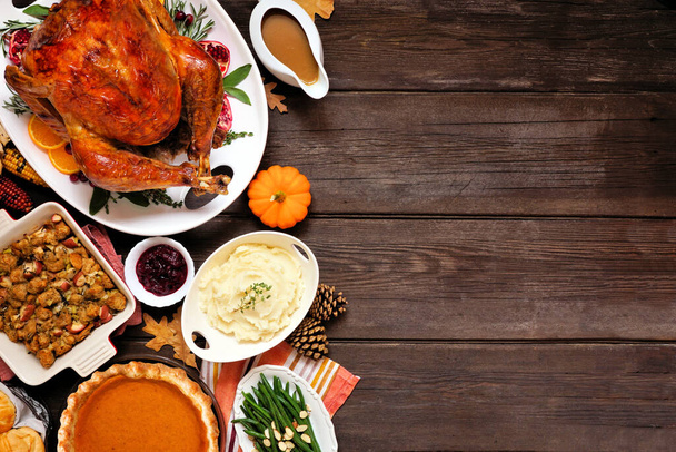 Classic Thanksgiving turkey dinner. Top down view side border on a dark wood background with copy space. Turkey, mashed potatoes, stuffing, pumpkin pie and sides. - Foto, imagen