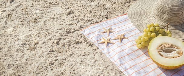 Half a melon, grapes, starfish on the beach. Top view, flat lay. Banner. - Photo, Image