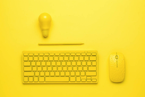 黄色の背景にマウス、鉛筆と電球を持つ黄色のキーボード。ビジネスとミニマリズムの概念。モノクローム. - 写真・画像