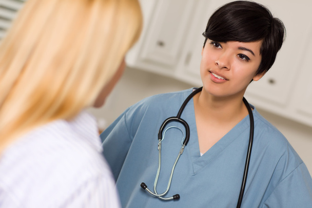 atrakcyjny mieszanej rasy młodego lekarza kobieta rozmawia z pacjentem - Zdjęcie, obraz