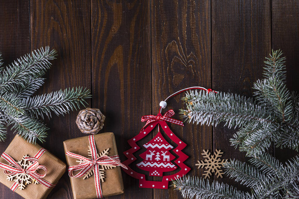 Karácsonyi kártya egy ajándék, fenyő ágak és szezonális dekorációk egy rusztikus fa asztal háttér. Felülnézet másolási hellyel a szöveghez. - Fotó, kép