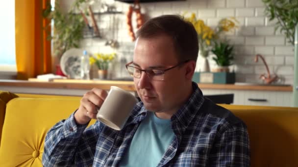 Een man met een bril die koffie drinkt in de keuken. 4k-beelden - Video
