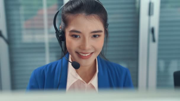 Mulher de negócios usando fone de ouvido trabalhando ativamente no escritório - Filmagem, Vídeo